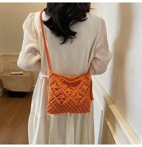 Detail of orange hand-woven macrame bucket bag with fringe and braided strap