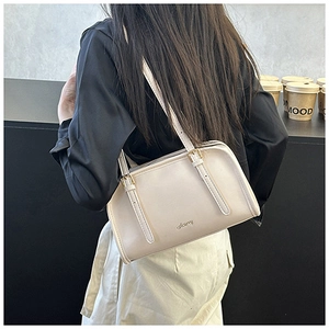 Vista posteriore dettagliata di una borsa a spalla color crema indossata da una modella