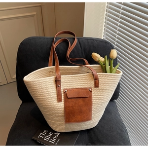Detail of woven tote bag with brown leather pocket and strap on a chair