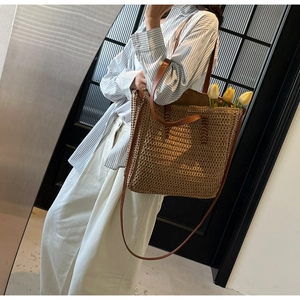 Detailed close-up of woven straw tote bag with brown leather handles and interior tulips