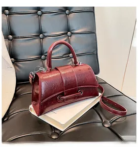 Detail of burgundy vintage hourglass handbag with oil-wax texture on a leather chair