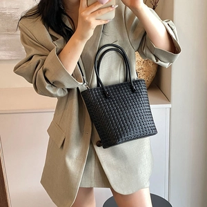Minimalist black woven tote bag with leather handles in a stylish commute style