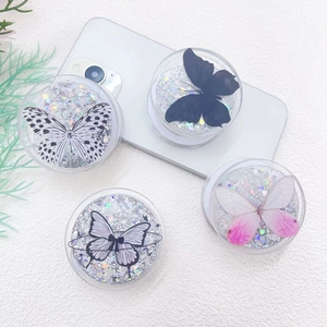 Detailed view of four circular glitter phone grips featuring unique butterfly patterns