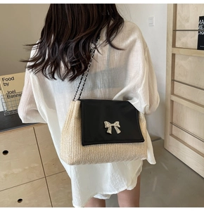 Détail du sac bandoulière en paille tressée avec rabat noir et boucle nœud argenté