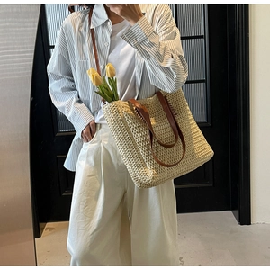 Detail of straw woven tote bag featuring brown leather handles and interior tulip decor