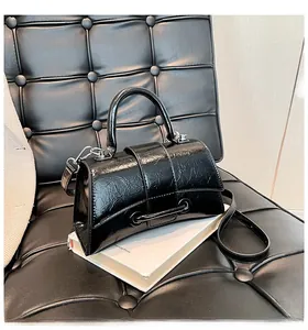 Detail of black hourglass handbag with glossy wrinkled leather texture and thin shoulder strap