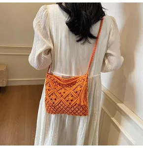 Detail of orange hollow knit bucket bag featuring long tassels and woven shoulder strap