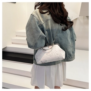 Detail of floral embroidery and retro metal kiss-lock on a stylish crossbody bag
