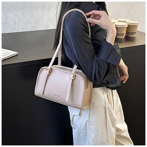 Dettaglio di una borsa a spalla in pelle beige crema dal design sobrio e tracolle sottili
