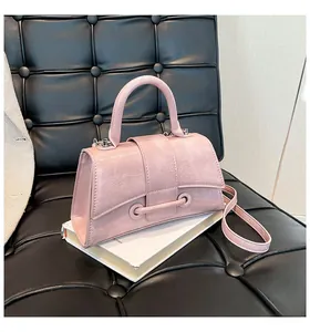 Detail of light pink wrinkled leather handbag with curved handle on a black sofa
