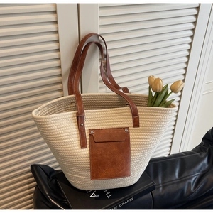 Detailed close-up of woven tote bag with brown leather handle and contrast stitching detail