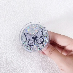 Close-up of a silver glitter phone grip featuring a butterfly design and planetary rings