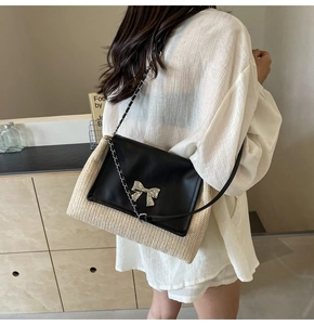 Détail du sac bandoulière en paille tissée avec rabat en cuir noir et nœud argenté
