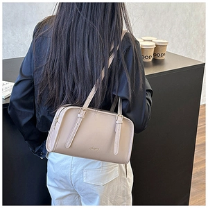 Dettaglio borsa a spalla beige in pelle con logo dorato e spalline sottili regolabili