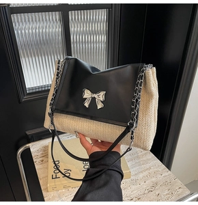 Détail du sac à bandoulière en paille avec rabat en cuir noir et nœud argenté
