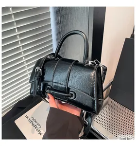 Detail view of black glossy wrinkled texture handbag with silver hardware and top handle