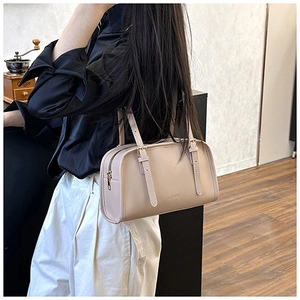 Dettaglio della borsa a cuscino in pelle beige minimalista con cerniera dorata e tracolla
