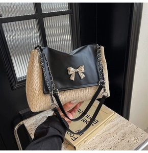 Détail du sac en paille tressée beige avec rabat en cuir noir et nœud argenté