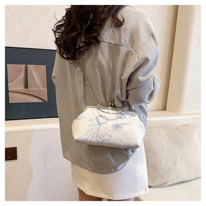Detailed view of vintage floral embroidery and metallic kiss-lock on the cream handbag