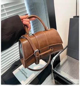 Detail of a brown PU leather hourglass handbag with pleated texture and silver buckle