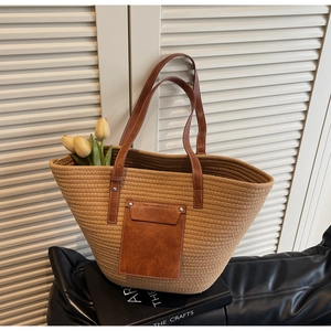 Detailed shot of a woven tote bag featuring brown leather straps and a studded pocket