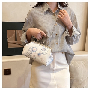 Detailed view of pearl white bag with floral embroidery and elegant metal chain strap