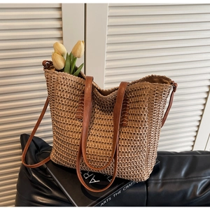 Detail of hand-woven straw tote bag with brown leather straps and yellow tulip decor
