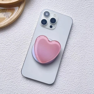 Detail of pink resin heart-shaped MagSafe phone grip on a white smartphone