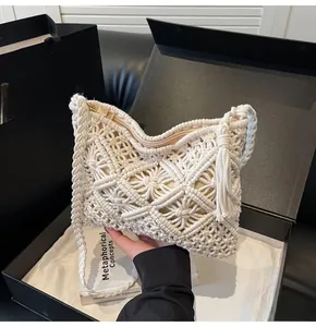 Close-up of cream knit bucket bag featuring hollow woven pattern and tassel detail