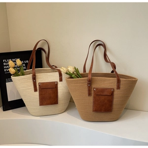 Detail of woven straw tote bags with faux leather pockets and white stitching on display