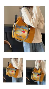 Détail du sac en toile jaune avec broderie légumes et bandoulière à carreaux noirs et blancs