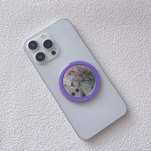 Detail of purple magnetic makeup mirror phone grip attached to white smartphone back