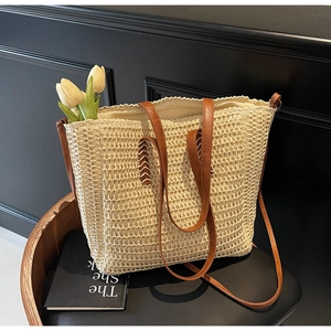 Detail of French straw beach bag featuring scalloped edges and leather handles