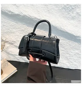 Close-up of black pleated patent leather hourglass bag with silver metallic hardware detail