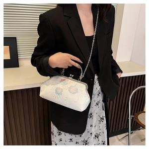 Detailed view of floral embroidery on a white silk handbag with silver chain strap