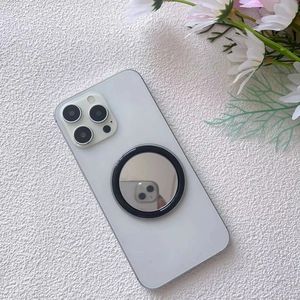 Macro shot of circular MagSafe makeup mirror accessory attached to white smartphone