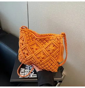 Detailed view of bright orange macramé knit bucket bag with long bohemian tassels
