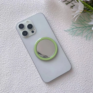 Close-up of a light green magnetic makeup mirror attached to a white smartphone