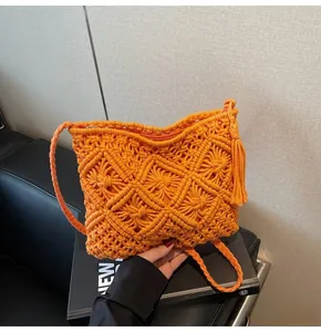 Detail of vibrant orange hand-woven knit bucket bag featuring a zipper and tassel charm