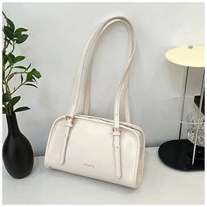 Dettaglio di una borsa a tracolla bianco crema minimalista con logo dorato sul davanti