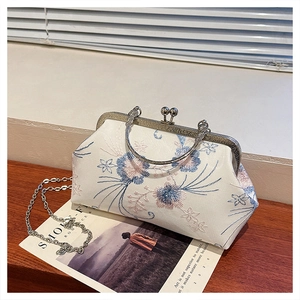 Detail of vintage floral embroidery on a white silk handbag with a metal kiss-lock frame