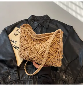 Detailed close-up of beige knitted bucket bag with fringe tassels on black leather jacket