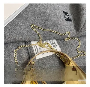 Detailed top view of a gold metallic crescent bag with chain on grey fabric