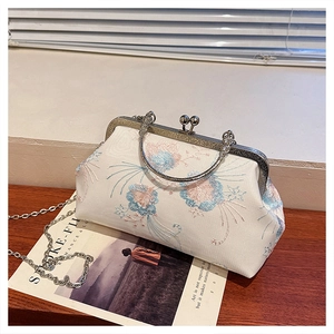 Macro detail of floral embroidery on a vintage cream kiss-lock bag with metal handle