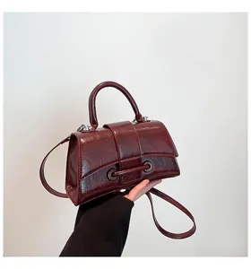 Close-up of wine red hourglass handbag with vintage oily leather texture and metal buckle