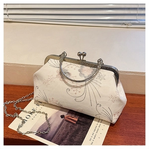 Detail of vintage floral embroidered clutch with silver ring handle on rustic wood