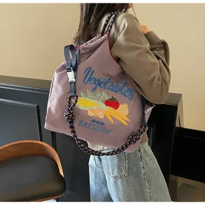 Détail du sac cabas en nylon violet avec broderie de légumes et bandoulière tissée