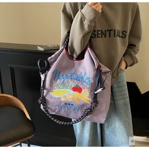 Détail du sac en toile violet avec broderie de légumes et bandoulière en corde tressée