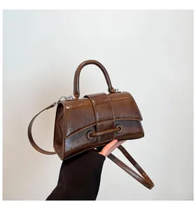 Detail of brown glossy hourglass handbag with pleated texture and stylish metal rings