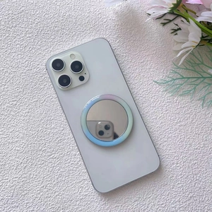 Close-up of a portable magnetic mirror phone stand attached to a white smartphone